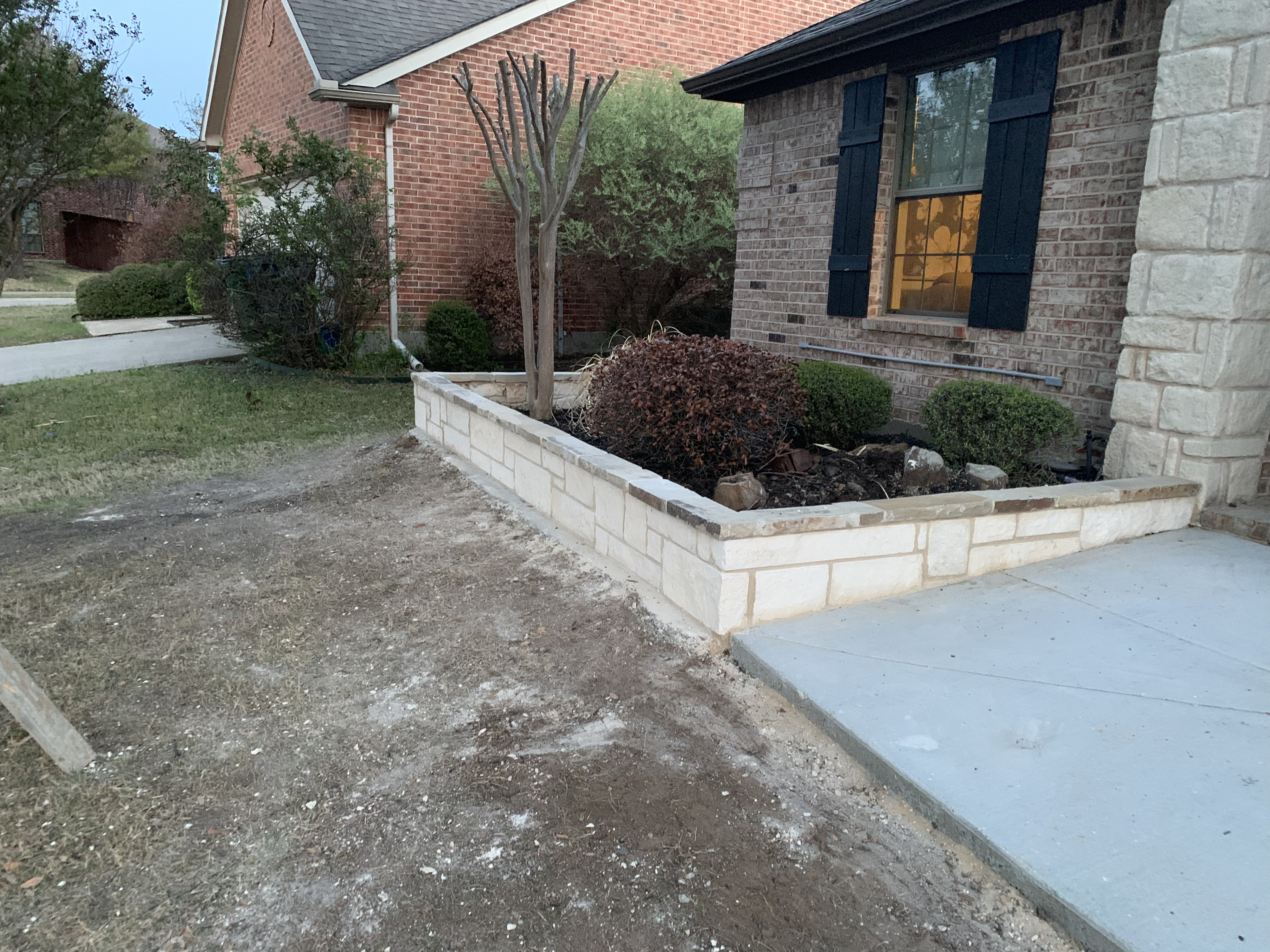 Custom stone planter wall built along driveway entry